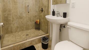 Ein Badezimmer mit Dusche, Waschbecken, Toilette und Mülleimer.
