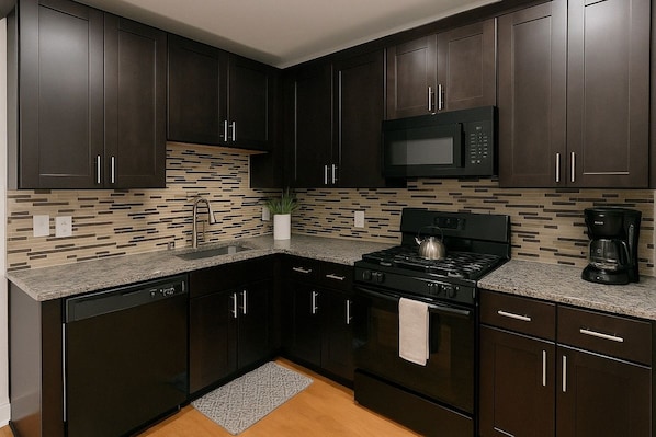 A modern kitchen with dark cabinetry, a microwave, a stove, and a coffee maker.