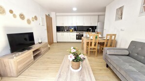 A modern living room with a flat-screen TV, wooden entertainment unit, and a grey sofa. A dining area with a wooden table and chairs is visible in the background. - A QUIET PLACE 5 MINUTES WALK FROM THE CENTER OF MONDARIZ. (Mondariz)
