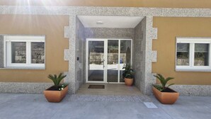 A building entrance with a glass door, two potted plants, and a paved area. - A QUIET PLACE 5 MINUTES WALK FROM THE CENTER OF MONDARIZ. (Mondariz)