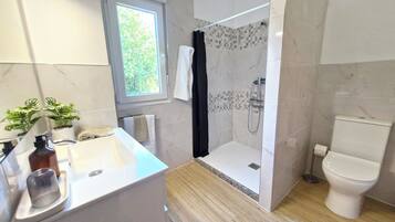 A modern bathroom with a shower, toilet, and sink.