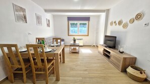 A dining area with a wooden table and chairs, a television on a wooden stand, and a window with a view of the outside. - A QUIET PLACE 5 MINUTES WALK FROM THE CENTER OF MONDARIZ. (Mondariz)