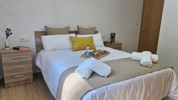 A neatly made bed with a tray of breakfast items, a bedside table with a book, and a wooden nightstand. - A QUIET PLACE 5 MINUTES WALK FROM THE CENTER OF MONDARIZ. (Mondariz)
