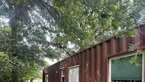 Un petit bâtiment d’un seul étage, doté d’une terrasse et d’un espace extérieur aménagé pour s’asseoir.