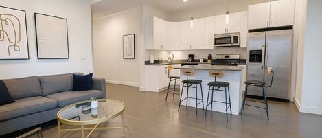 A modern kitchen with white cabinets, stainless steel appliances, and a bar area with stools.