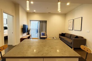 Una sala de estar moderna con una gran mesa de mármol, un sofá y un televisor.