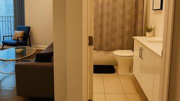 Un baño moderno con inodoro, cortina de ducha y un lavamanos pequeño.