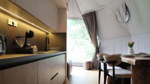 A modern kitchen with a built-in espresso machine, a dining area with a wooden table and chairs, and a large window providing natural light.