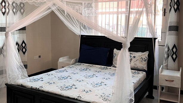 Un dormitorio con cama con dosel, ventilador de techo y ventana con vistas al exterior.