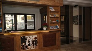 Ein Empfangstresen mit Holzoptik, eine Schilder über ihm und ein Blick ins Freie durch Glastüren.