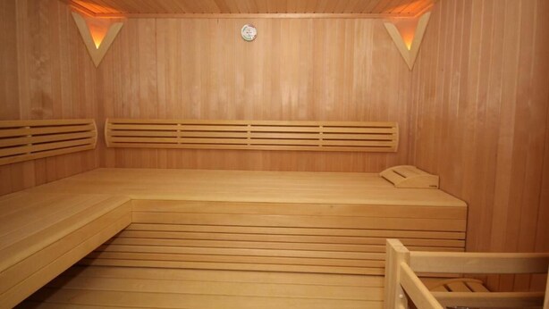 Eine Sauna mit Holzbänken, schrägläufigem Boden und einem Oberlicht.