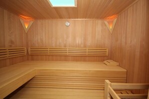 Un sauna avec des bancs en bois, un sol incliné et une lucarne.