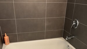 Et badeværelse med badekar, toilet og to toiletartikler.