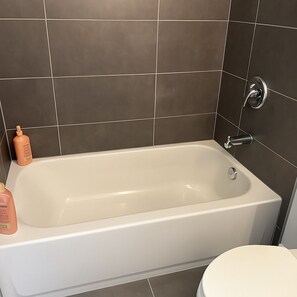 Une salle de bain équipée d’une baignoire, de toilettes et de deux flacons de produits de toilette.