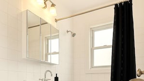 Un baño con inodoro, lavamanos, espejo y bañera.