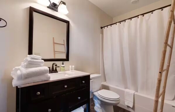 Un baño con lavamanos, espejo e inodoro.