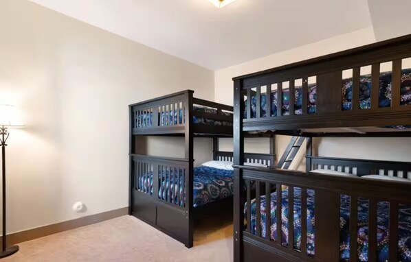 Una habitación con literas, una lámpara de pie y suelo alfombrado.