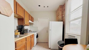 A compact kitchen with wooden cabinets, a white refrigerator, a microwave, and a stove. - Paradise 1BR Apt in Lincoln Park (Chicago)