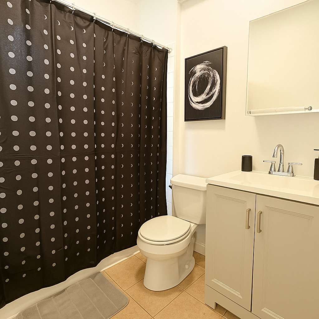 Une salle de bain équipée de toilettes, d’un lavabo et d’un rideau de douche à motifs à pois.