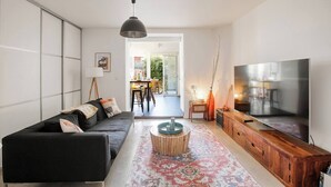 Ein modernes Wohnzimmer mit einer schwarzen Couch, einem Holz-TV-Schrank und einem großen Flachbildfernseher.