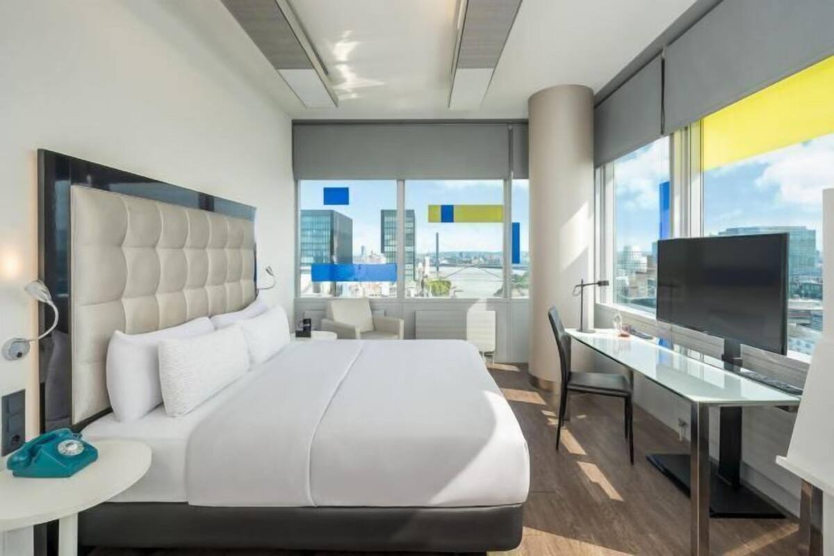 Ein modernes Hotelzimmer mit einem großen Bett, einem Schreibtisch und einem Fernseher.