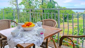A balcony with a table set for two, featuring a bowl of fruit, two cups, and a decorative plate. - Gorgeous apartment in Ricadi (Ricadi)