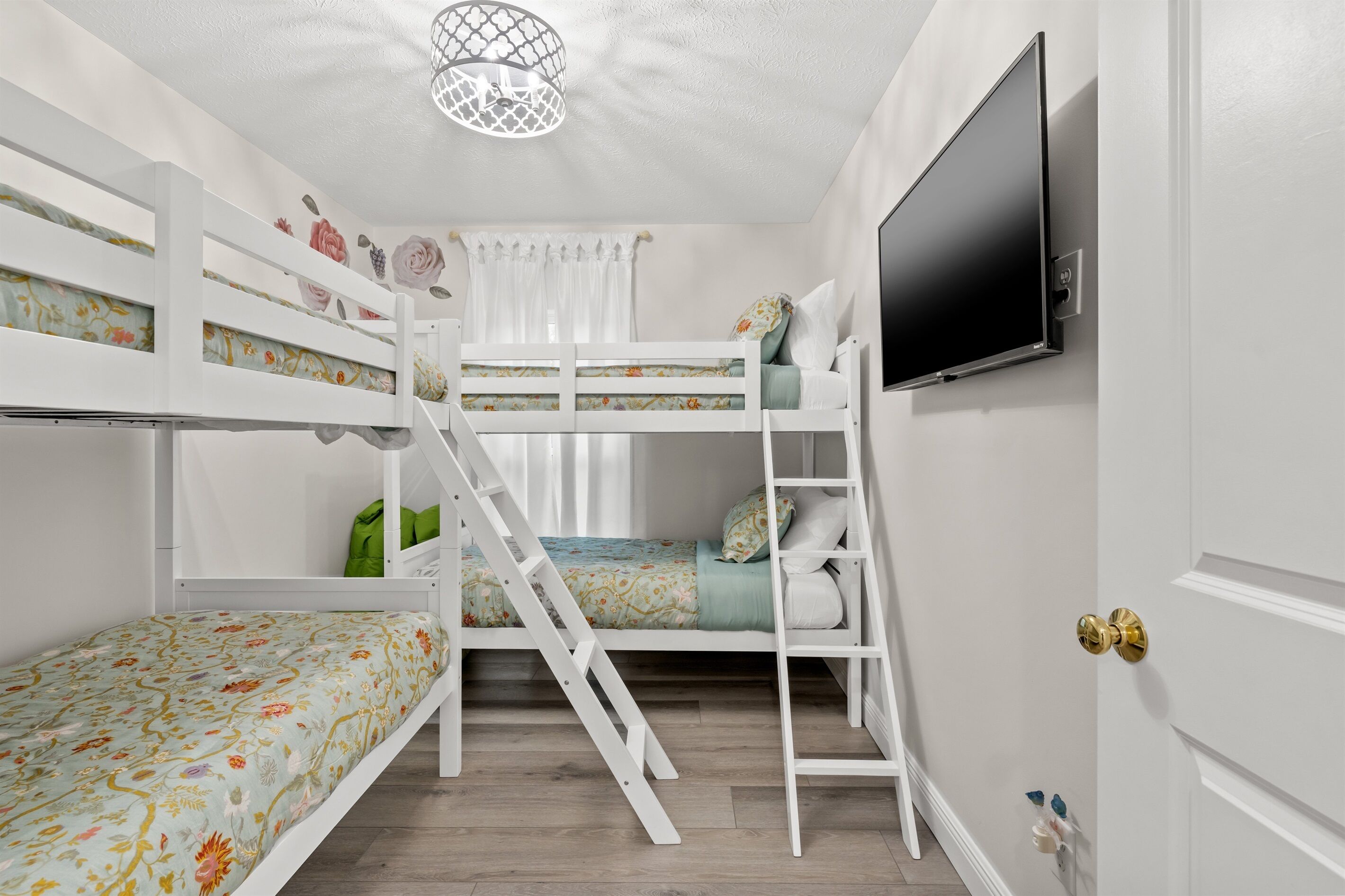 A bunk bed room with a TV on the wall, a ladder, and a door with a golden handle.