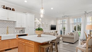 Une cuisine moderne avec des meubles blancs, un îlot central et un luminaire suspendu.