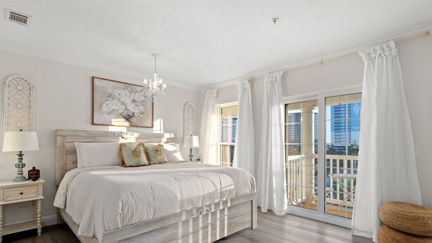 Une chambre dotée d’un grand lit, d’un lustre, d’un balcon avec vue et d’un élément décoratif mural.