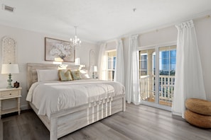 Ein Schlafzimmer mit einem großen Bett, einer Kristallleuchter, einem Balkon mit Blick und einem dekorativen Wandbild.