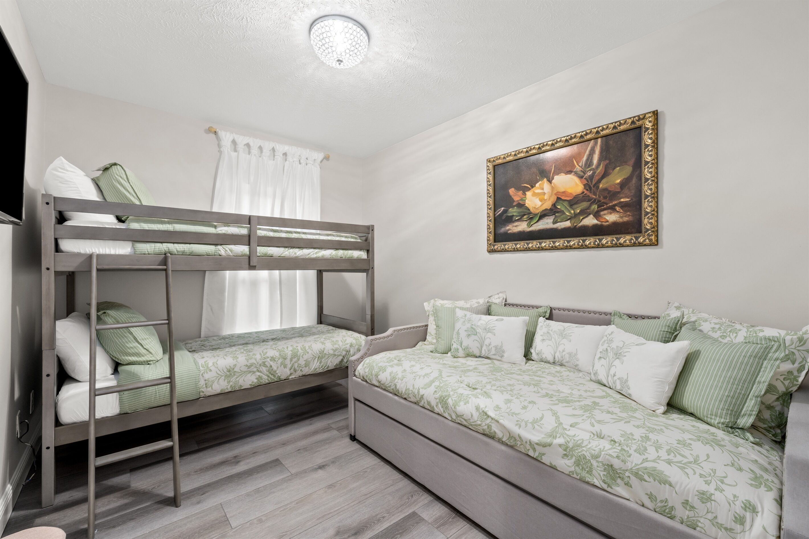 A bunk bed with a lower bunk and a sofa bed with floral bedding.