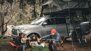 A camping scene with a vehicle, a tent, and a green cooler. - The Shepherd Company (Coyhaique)