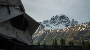 A tent in the foreground with a mountainous landscape in the background. - The Shepherd Company (Coyhaique)
