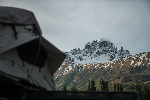 A tent in the foreground with a mountainous landscape in the background. - The Shepherd Company (Coyhaique)