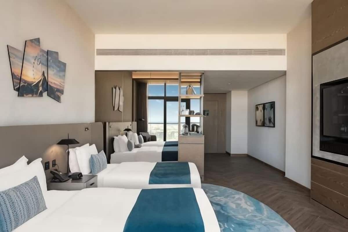 Une chambre dâhĂŽtel avec deux lits, une tĂ©lĂ©vision, des Ćuvres dâart et une vue sur la ville.