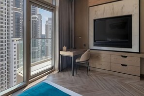 A modern room with a large window, a desk, a chair, and a TV mounted on the wall. - Paramount Hotel Midtown (Dubai)