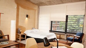 Een hotelkamer met een bed, een bureau, een stoel, een lamp en uitzicht op buiten.