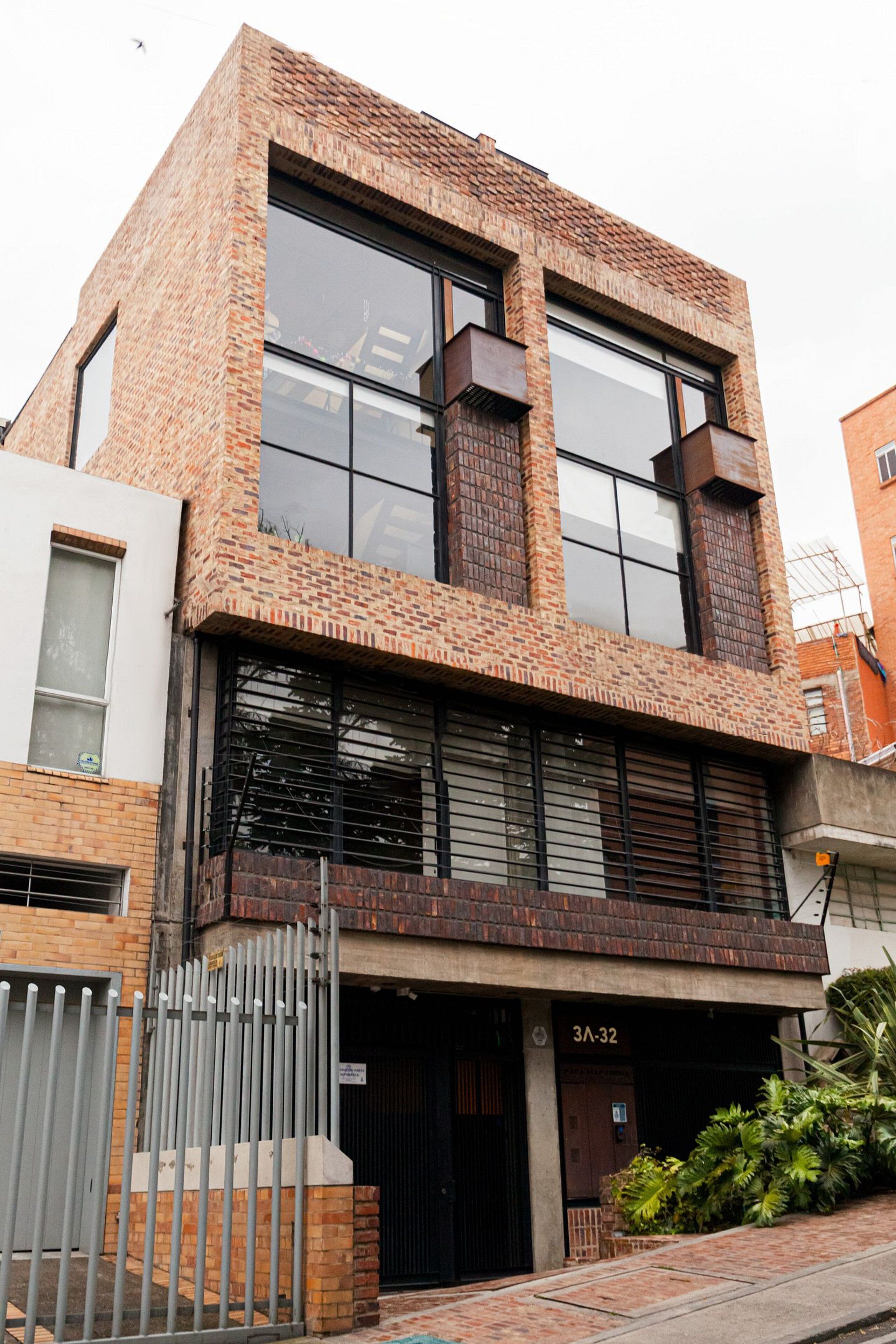 A modern two-story building with large windows, a brick facade, and a gated entrance.