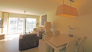 Una sala de estar moderna con un sofá, sillones, una mesa de comedor y un ventanal con vistas a la ciudad.