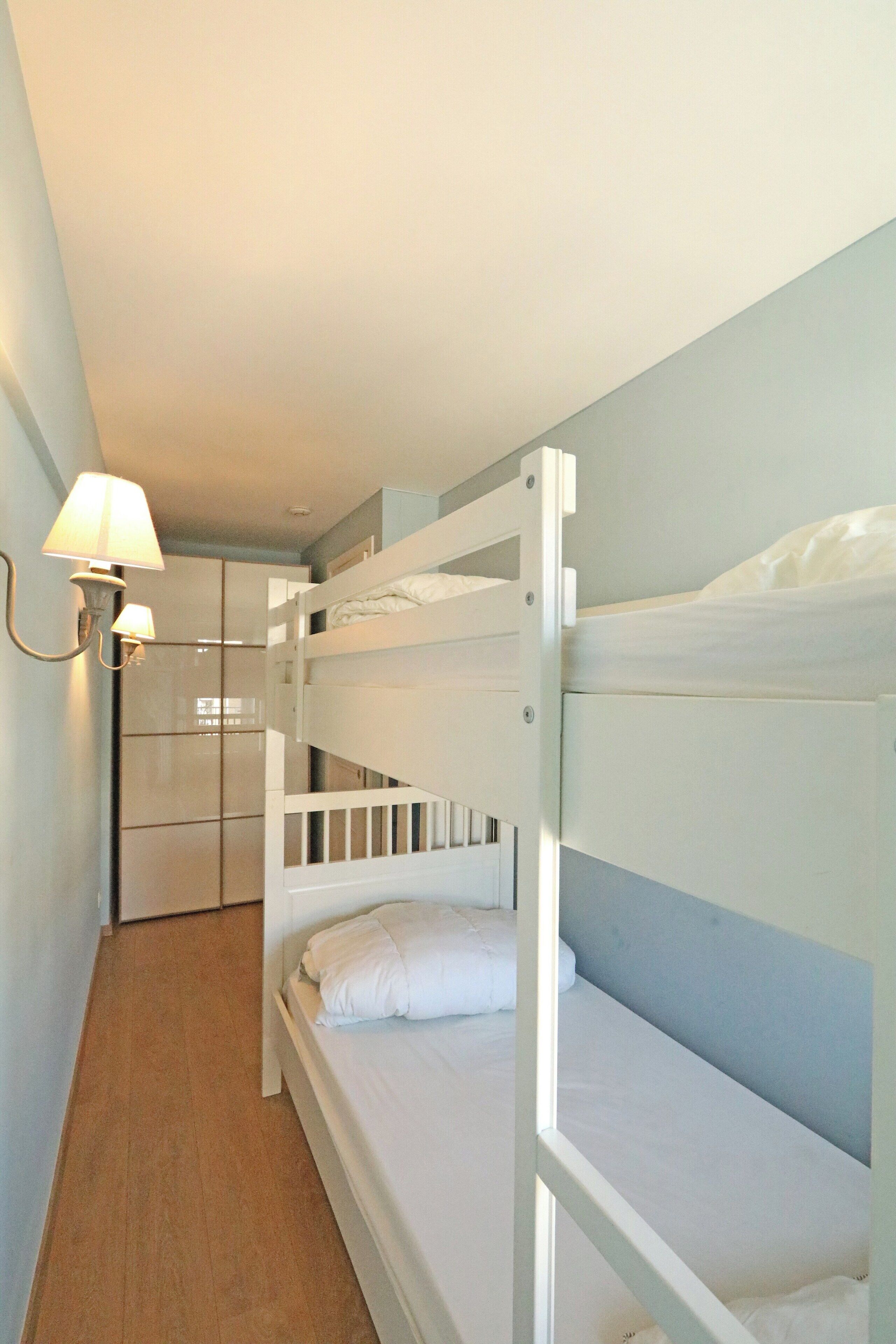 Een slaapkamer met stapelbed, een garderobe en een lamp.