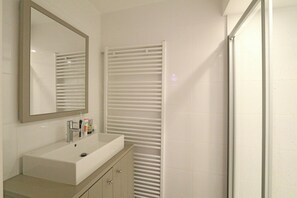 Une salle de bain avec un lavabo blanc, un miroir et un porte-serviettes.