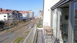 A balcony with a view of a city street, a construction crane, and modern buildings. - Apartment in Knokke Near Zeedijk Beach (Knokke-Heist)