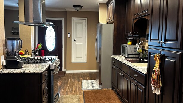 Una cocina moderna con armarios de madera oscura, un refrigerador de acero inoxidable, una estufa a gas y un microondas.