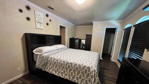 Un dormitorio con cama, cómoda y puerta que da a otra habitación.