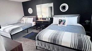 Une chambre d’hôtel avec deux lits, un bureau, une chaise, un miroir et un ventilateur de plafond.
