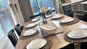 Une table à manger dressée avec de l’assiette et des bols blancs, ainsi qu’un centre de table.