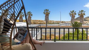 A balcony with a view of palm trees and a distant town.