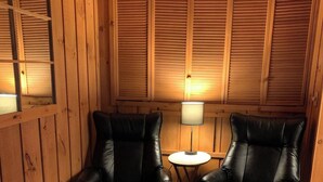 Una stanza con due poltrone in pelle nera, un tavolino rotondo con una lampada e pannelli di legno alle pareti.