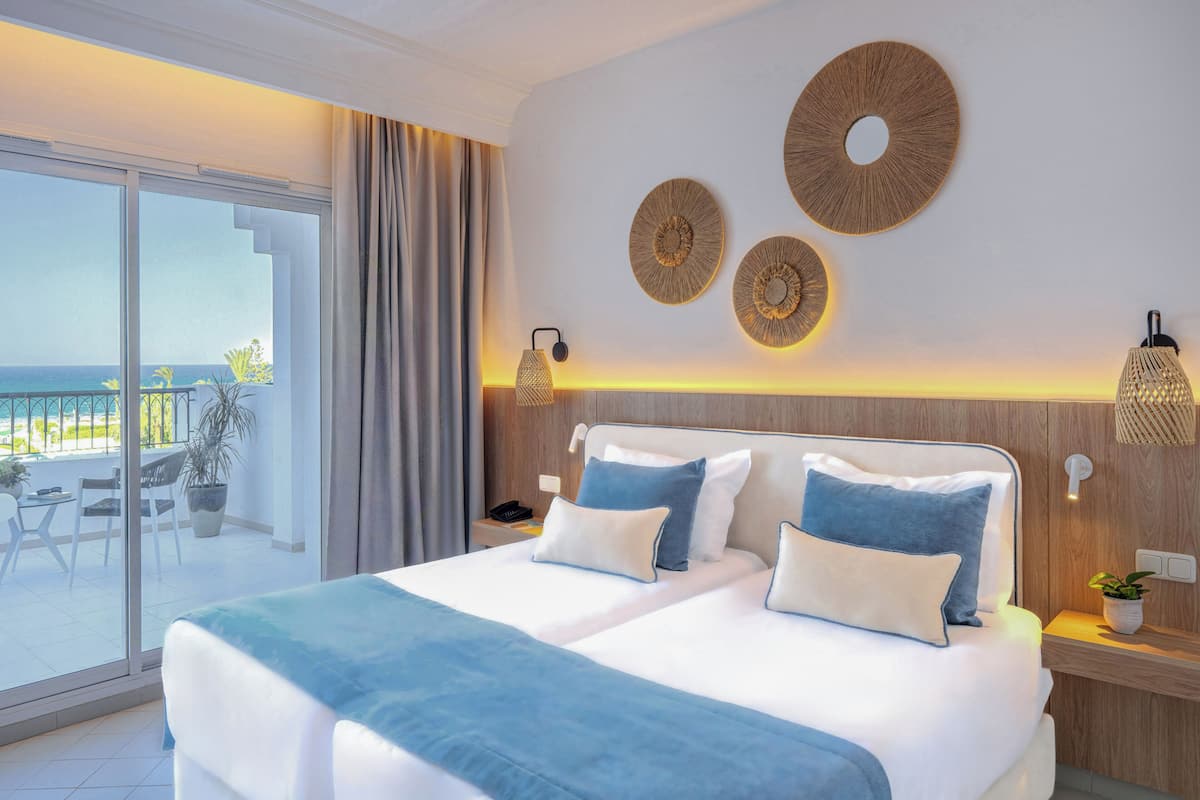 Una habitación de hotel con una cama grande, un balcón con vistas y decoración en la pared.