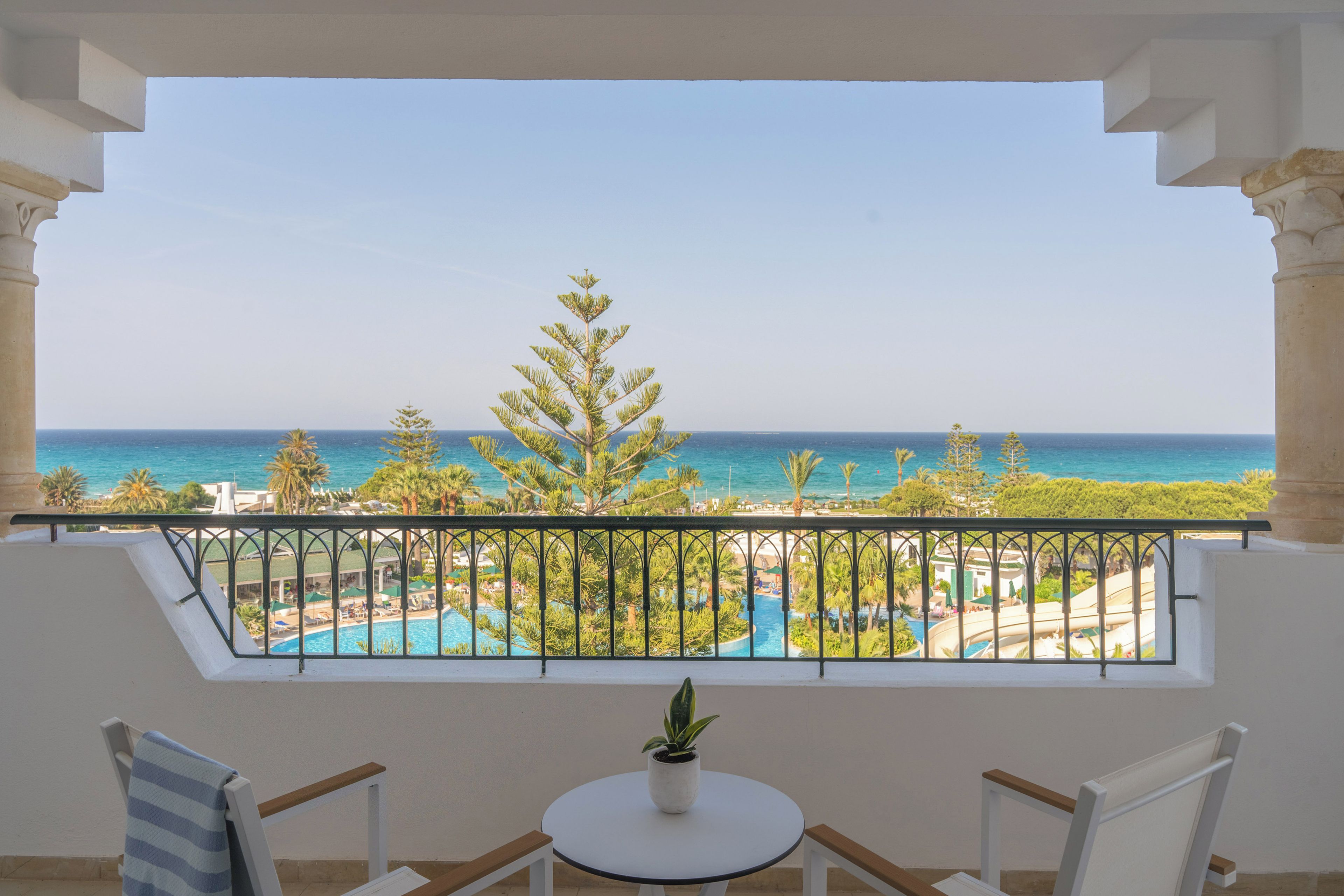 Ein Balkon mit Blick auf einen Pool und das Meer.